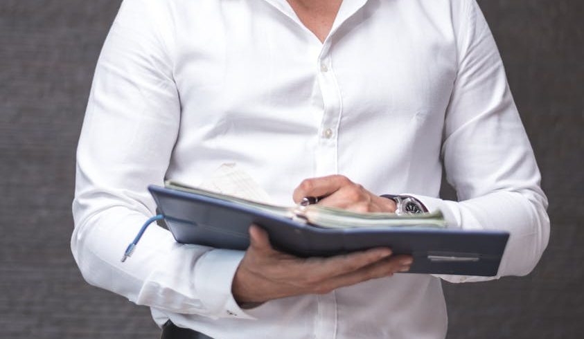 man in white dress shirt holding a planner